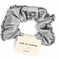 Silver scrunchie with chain detail and a card on a white background